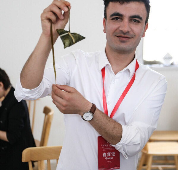 Mohammad Hashem Mohammadi, a Shanghai-based Afghan content creator, poses for photo holding a zongzi in Weihai, East China’s Shandong province, on June 7, 2024. [Photo provided to chinadaily.com.cn]